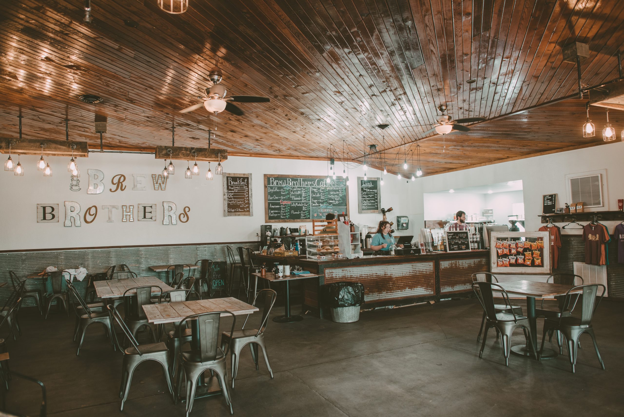 Brew Brothers Coffee storefront interior in Eldon, Missouri; a spacious local cafe with a full espresso bar, breakfast menu, and rustic industrial decor.